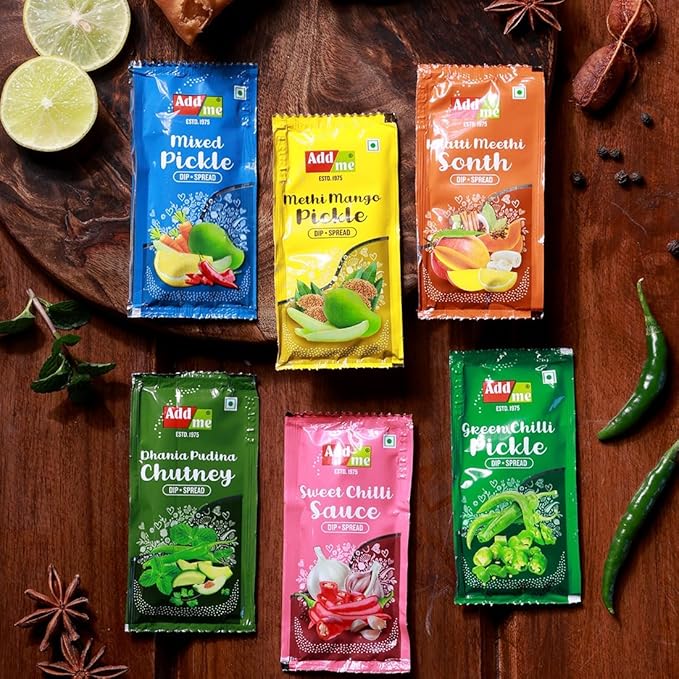 Assorted packets of Addme pickles and chutneys on a wooden surface with spices and ingredients.