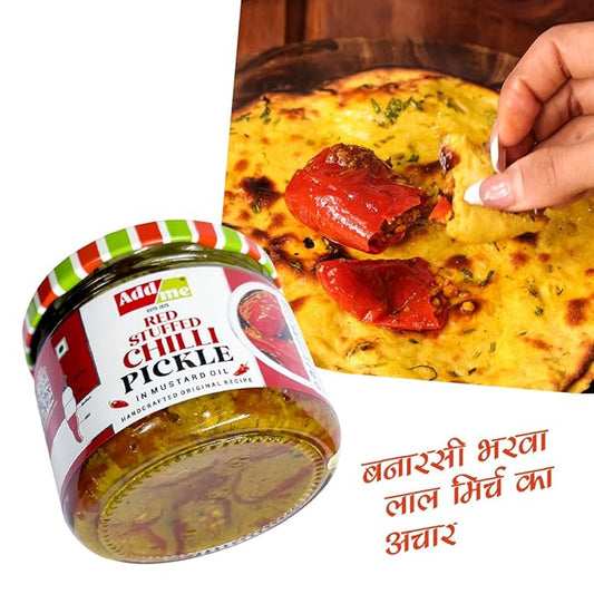 Jar of red stuffed chilli pickle with a hand holding a piece of naan with pickle on it.