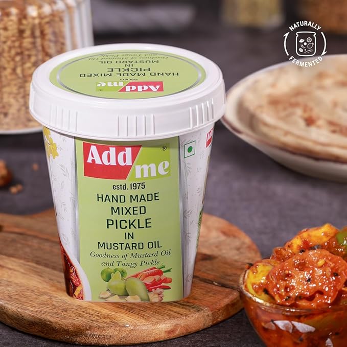 Container of Add Me hand made mixed pickle with mustard oil on a wooden board.