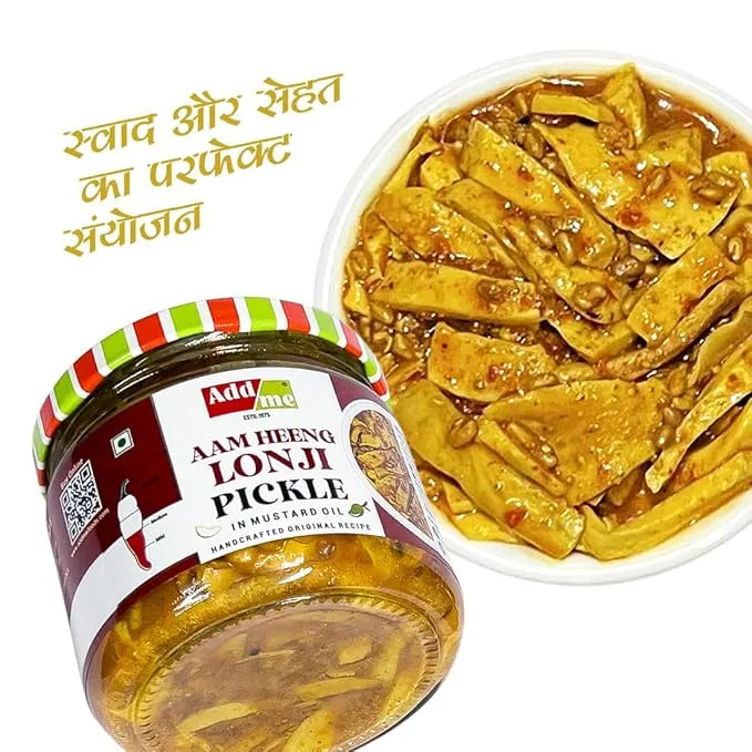 Jar of Add Me Aam Heeng Lonji Pickle with a wooden bowl of pickles on a white background
