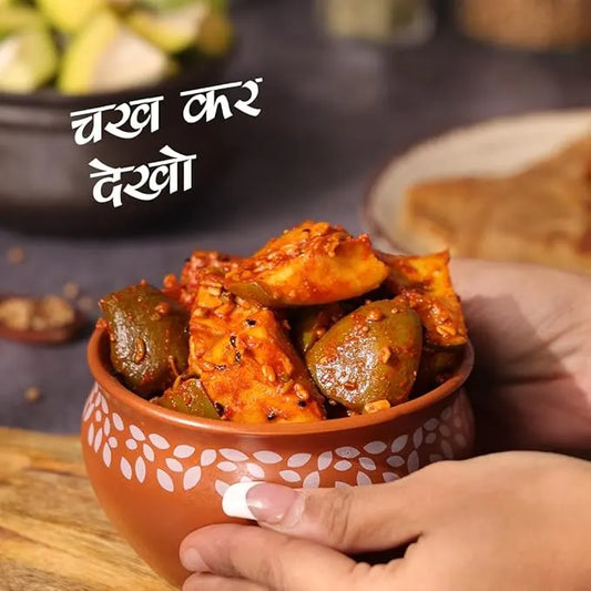 Cucumber pickle in a terracotta bowl held by a hand with text overlay