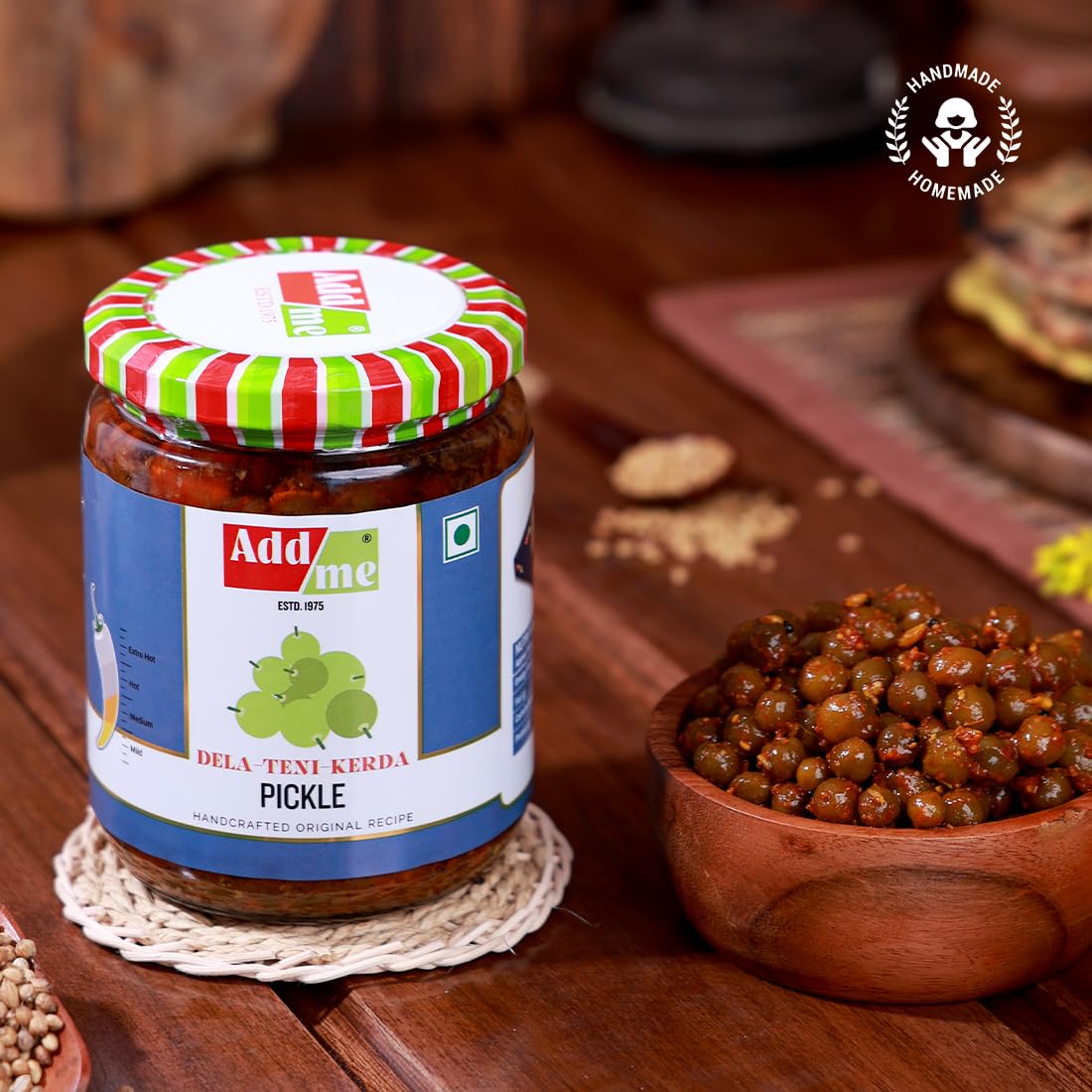 Jar of Add Me pickle with a wooden bowl of pickles on a wooden surface