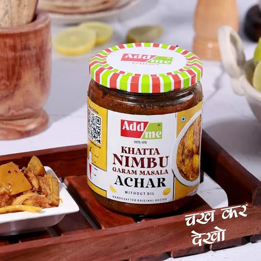 Jar of Add Me Khatta Nimbu Garam Masala Achar on a wooden tray with food items in the background.