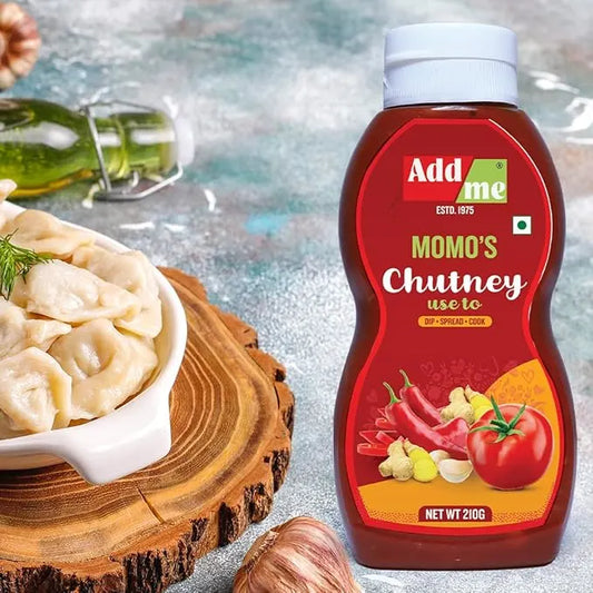 Bottle of Add Me Momo's Chutney with a bowl of dumplings on a wooden surface.