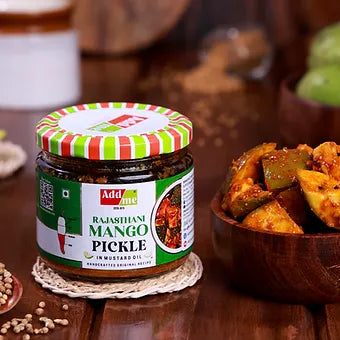 Jar of Rajasthan Mango Pickle on a wooden surface with a bowl of pickles.
