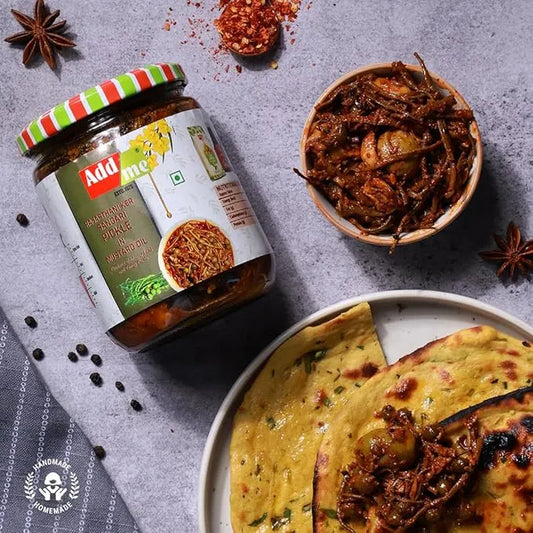 Jar of Add Me curry paste with a bowl of curry and flatbread on a gray surface.