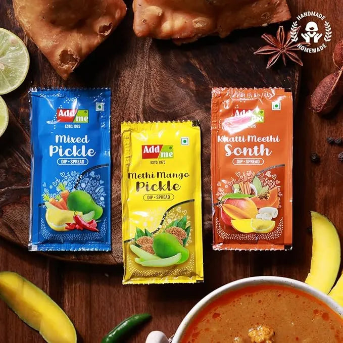 Three Addmi pickle packets on a wooden surface with food items around