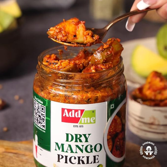 Jar of Add Me Dry Mango Pickle with a spoonful being lifted, surrounded by fruits.