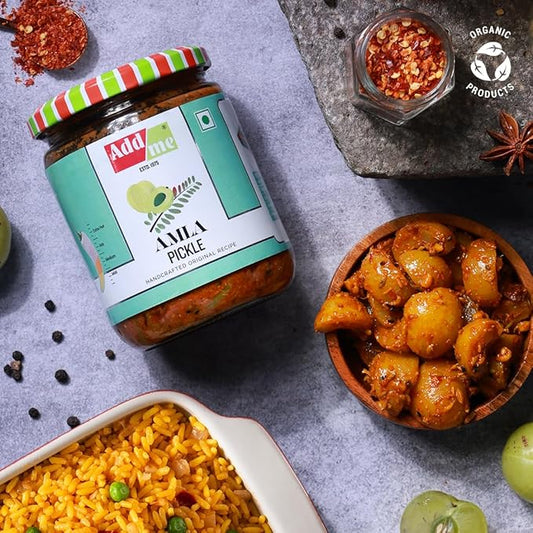 Jar of Amla pickle with a bowl of food and spices on a gray surface