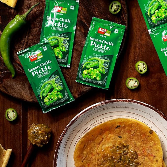 Add Me Foods: Green Chilli Pickle packets on a wooden surface with a bowl of food.