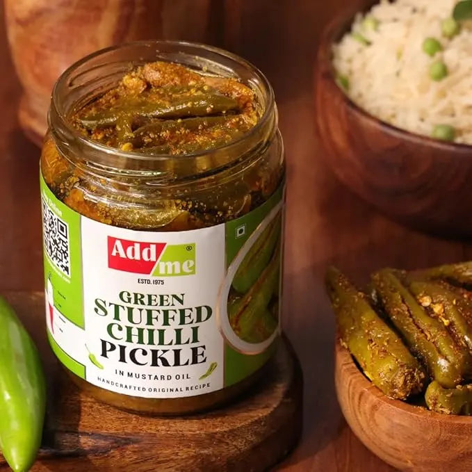 Jar of green stuffed chilli pickle with 'Add me' label on a wooden surface. chilli pickle