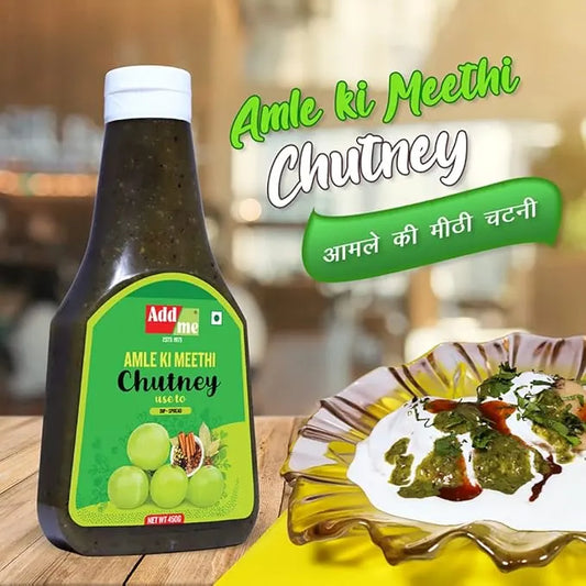 Bottle of 'Amle ki Meethi Chutney' with a plate of food on a wooden table.