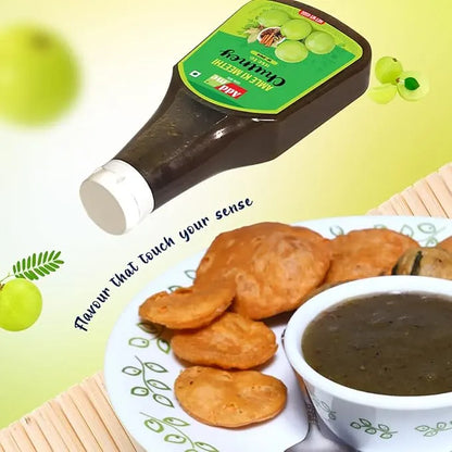 Bottle of grape jelly with a plate of cookies and a bowl of dark sauce on a light green background.