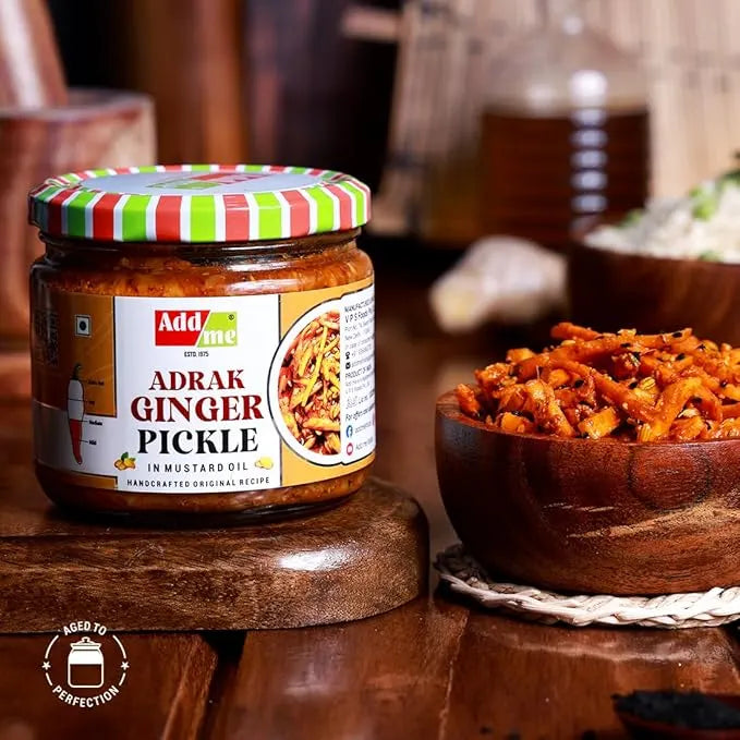 Jar of Adrak Ginger Pickle with a striped lid on a wooden surface, next to a bowl of pickled ginger.