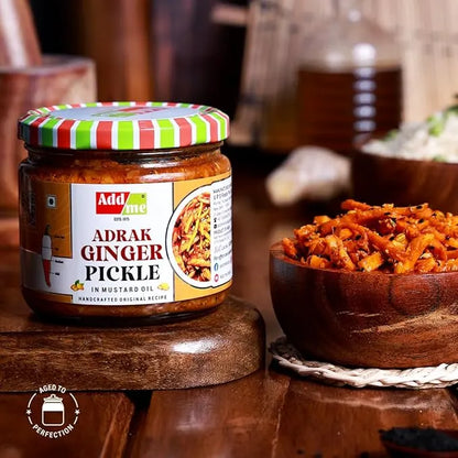 Jar of Adrak Ginger Pickle with a striped lid on a wooden surface, next to a bowl of pickled ginger.