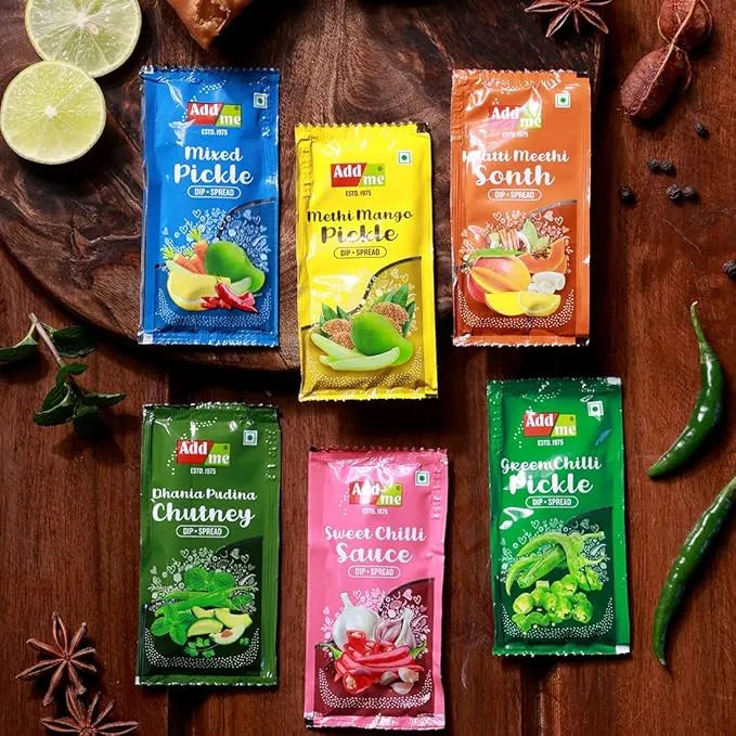 Assorted packets of Addme pickles and chutneys on a wooden surface with spices and ingredients.