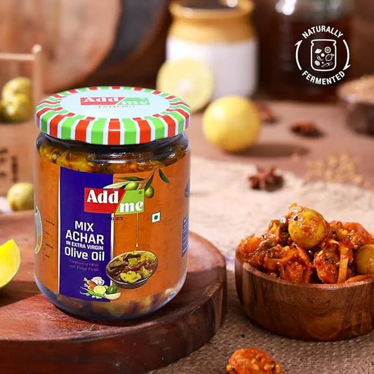 Jar of Add Me Mix Achar with a bowl of pickled vegetables on a wooden surface.
