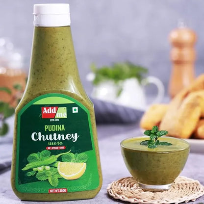 Bottle of Adda Pudina Chutney with a bowl of chutney and snacks in the background
