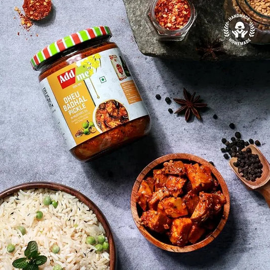 Jar of Dhabal pickle with a bowl of rice and pickled items on a gray surface.