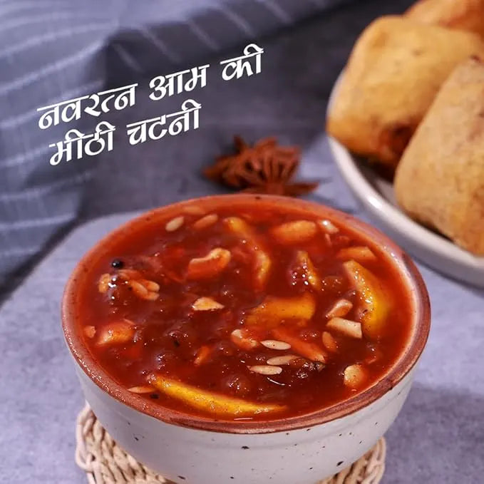 Bowl of red chutney with bread on a textured surface, mango chutney