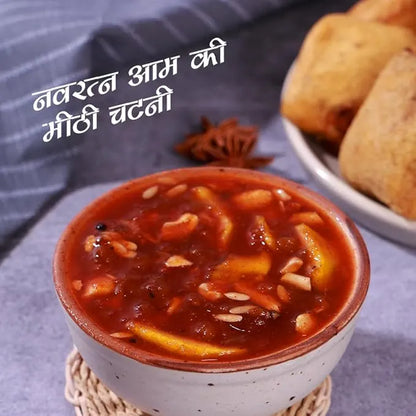 Bowl of red chutney with bread on a textured surface, mango chutney