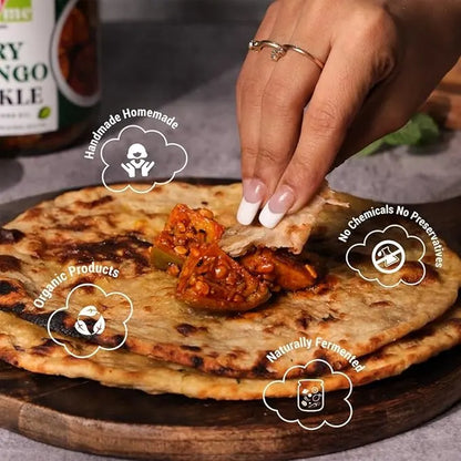 Person dipping a piece of flatbread into a bowl of red sauce on a wooden board.