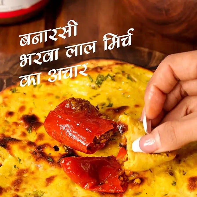 Person dipping a piece of food into a bowl with text overlay. mango pickle, chilli pickle