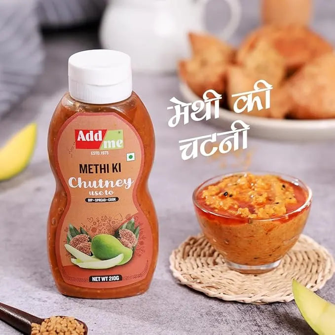 Bottle of Add Me Methi Ki Chutney with a bowl of chutney and snacks on a table.