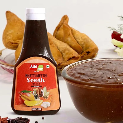 Bottle of Add Me Khatti Meethi Sonth with a bowl of the product and samosas in the background. sonth chutney