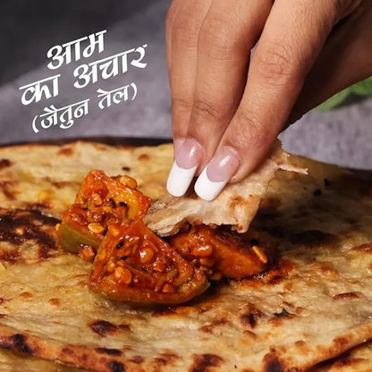 Hand dipping a piece of naan into a bowl of curry with text in a foreign language.