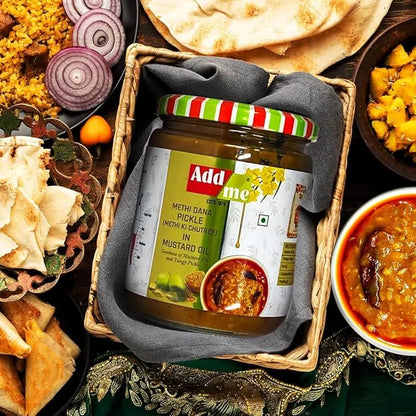 Jar of Add Me Methi Dana Pickle surrounded by Indian snacks and dishes