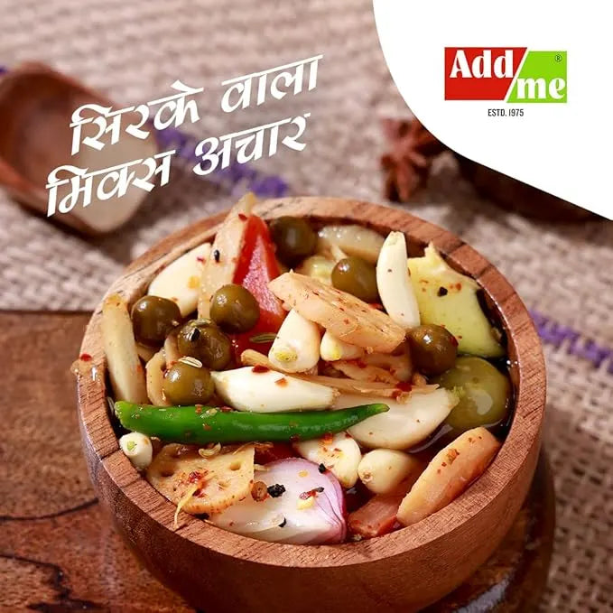 Wooden bowl of mixed pickles with spices on a textured surface, featuring AddMe logo.