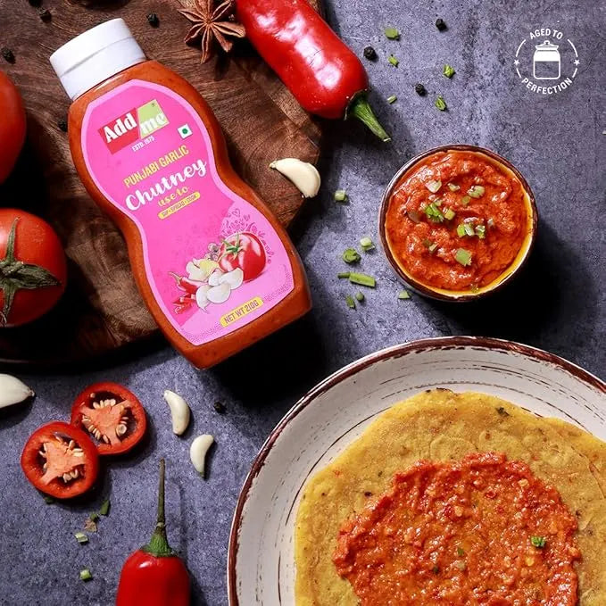 Squeeze bottle of Add Achi Punjabi Garlic Chutney with ingredients and a dish of chutney on a dark surface.
