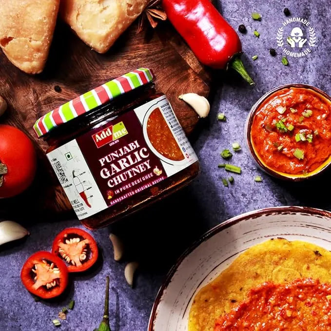 Jar of Punjabi Garlic Chutney with ingredients and a dish on a wooden board.