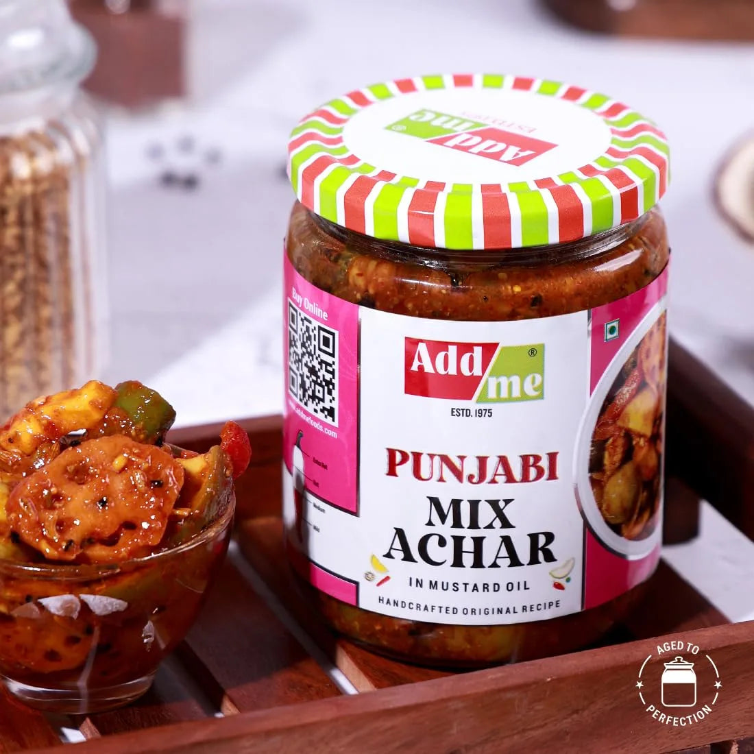 Jar of Add Me Punjabi Mix Achar with a colorful lid on a wooden tray.