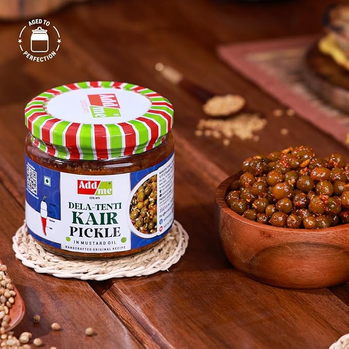 Jar of Dela-Tenti Kair Pickle with a striped lid on a wooden surface