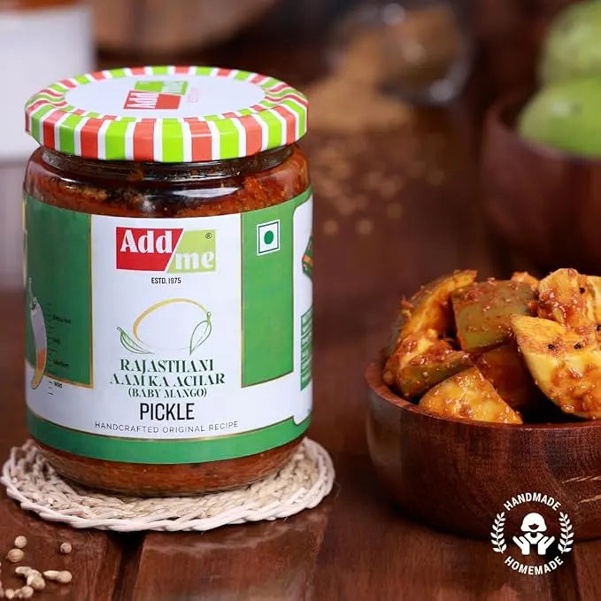 Jar of Add Some Rajasthani Aam Kaachar Pickle with a bowl of pickles on a wooden surface.