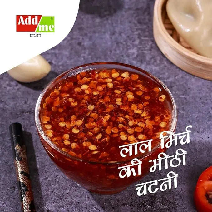 Add Me Foods: Glass bowl of red chili garlic chutney with Addme logo on a dark surface