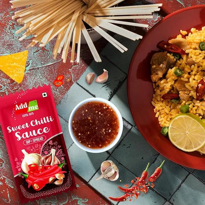 Add Me Foods: Add me Sweet Chilli Sauce packet with a dish of rice and vegetables, noodles, and lemon on a textured surface.