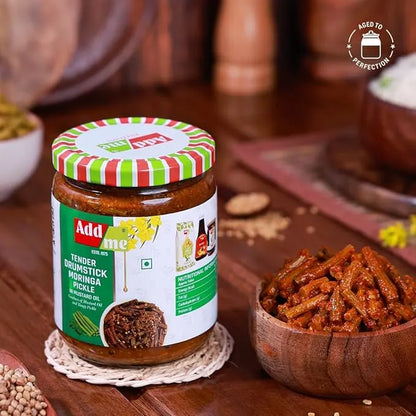 Jar of Add Me pickles on a wooden table with a bowl of pickles and spices.