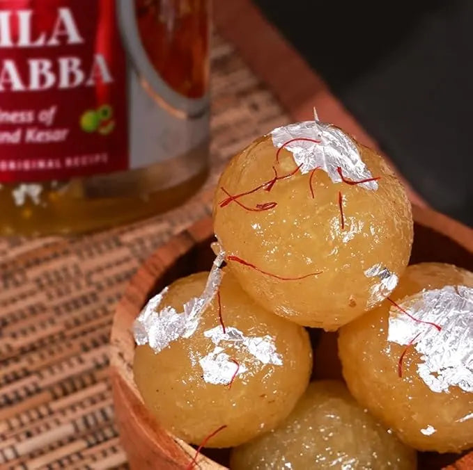 Add Me Foods: Candied fruits (Amla) with saffron threads in a wooden bowl with a bottle of Ila Abba in the background.