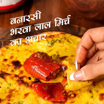 Person dipping a piece of food into a bowl with text overlay. mango pickle, chilli pickle